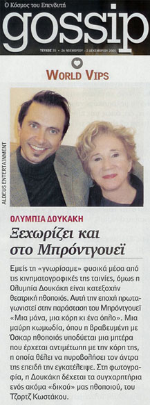 Newspaper clip: Gossip / weekend magazine of Investor's World (O Kosmos Tou Ependyti): Section: World VIPs. Title: "OLYMPIA DUKAKIS: She Stands Out on Broadway Too." Photo: Olympia Dukakis and George Costacos. Story Excerpt: "Of course we've "met her" through her movies, however Olympia Dukakis is a predominant (exceptional) theatrical actress. These days she's starring in "A mother a daughter and a gun." A black comedy, where the Oscar-winning actress plays a mother who comes face to face with her daughter, who wants to shoot her husband for abandoning her. In the photo, Dukakis receives congratulations from George Costacos."